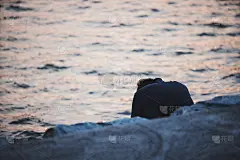 一个沮丧的人坐在河边看夕阳。