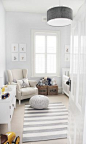 White and gray nursery features gray drum pendant, West Elm Short Drum Pendant, over white and gray stripe rug, CB2 Pull Up a Pouf on Crate & Barrel Olin Grey Rug, as well as linen slipcovered wingback glider accented with DL Rhein Embroidered Octopus