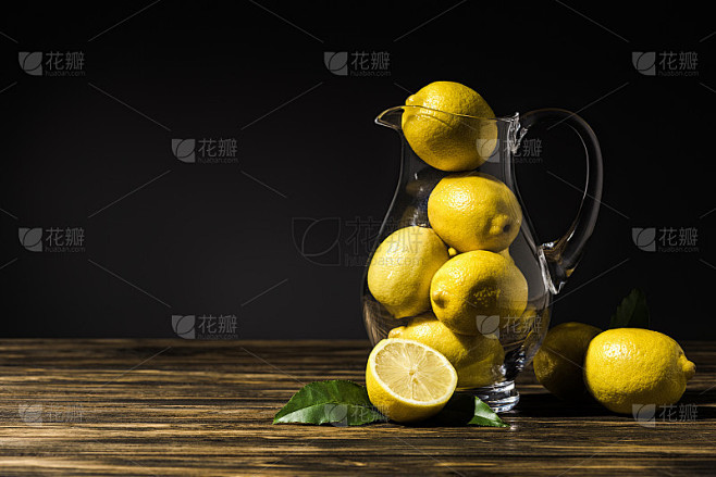 木桌上放着一个装有黄色柠檬的玻璃瓶