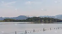 在中国杭州，游船在西湖和远处的山
