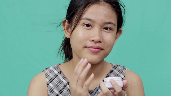 小女孩在脸上涂抹面霜，绿屏