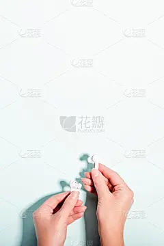 白色无线耳机在女性的手在柔和的背景，复制空间。现代科技平躺与无绳耳机在女性手中，现代生活理念