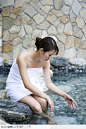 温泉SPA-坐在石上戏水的女子