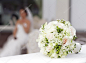 与坐在背景-浅景深的新娘美丽的白色婚礼花束