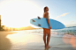 太平洋岛民女人携带冲浪板在海滩上的Gable Denims在500像素