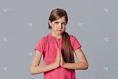 亲爱的，请帮帮我。可爱的年轻女孩的肖像在沮丧的微笑拉下嘴唇，在乞求道歉时皱着眉头，握着手掌，站在灰色