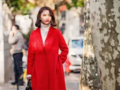 Beautiful young brunette woman wearing a red coat in autumn city. Outdoor fashion portrait of glamour young Chinese cheerful stylish lady in street. Emotions, people, beauty and lifestyle concept.