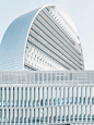 A white facade of a tall building with a rounded roof in Madrid