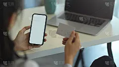 女性拿着智能手机和名片在办公室工作