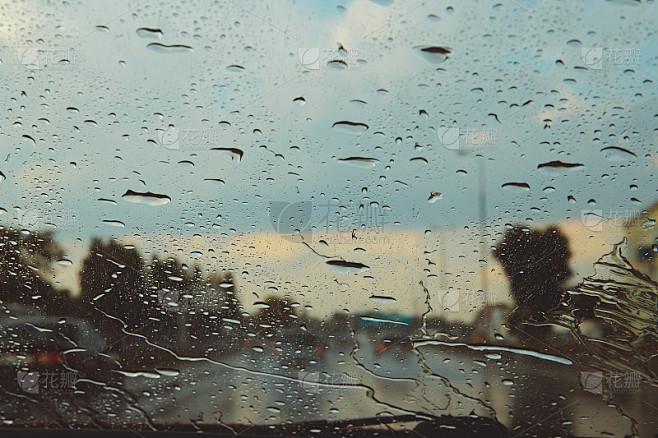 透过雨点看到的城市道路上的汽车挡风玻璃。