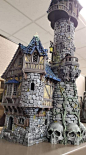 This may contain: a castle made out of rocks with skulls on the bottom and a clock tower in the middle