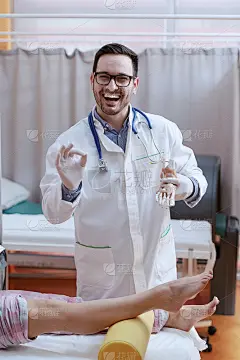 年轻微笑白种人医生在白色制服和听诊器周围的脖子在一只手脚模型和与另一只手显示好的迹象。在前景女人的腿