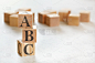 三个字母ABC(意思是总是关闭)的木方，在白色的桌子上，更多的背景，文字空间在右下角