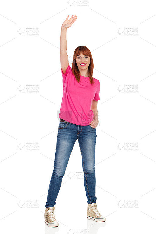 快乐的年轻女子举起手臂，挥舞着手站在那里