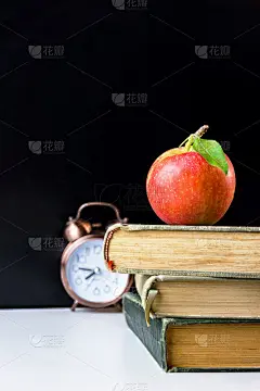 在教室里，白色的课桌上，黑色的黑板上有一个闹钟。回归学校教育知识学习学习理念。附有版面的海报