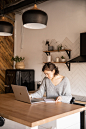 Focused female freelancer with laptop and notepad in kitchen