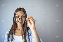 一个年轻女子在灰色背景下拿着一副眼镜的画室肖像。