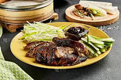 北京烤鸭是中国菜。黄色的盘子，蔬菜和酱汁放在深色的石板桌上。中国、亚洲、正宗的美食理念
