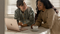 两位女性坐在餐桌旁，面前是一台 Surface Laptop 3