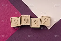 2022年新年。铭文是由环保的木制立方体在一个明亮的颜色趋势背景。简约的圣诞贺卡，珊瑚色和鲜红色的季