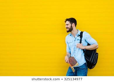 英俊的学生背包站在外面在黄色背景