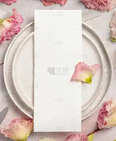 婚礼菜单放在大理石桌上的瓷盘上，上面装饰着鲜花和彩带。用空白纸制贺卡的模拟场景。女性平躺在床上
