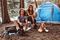 Free photo attractive young couple have a rest in summer forest. people are sitting near tent and bonfire.