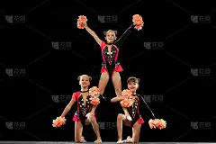 三个女孩的全身肖像，啦啦队长训练在舞台服装与绒球孤立在黑色背景