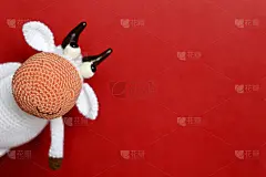 白色针织玩具公牛在红色的背景，新年贺卡免费复制空间的文字