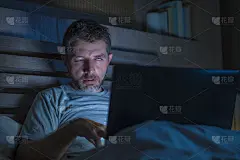 疲惫和压力大的工作狂工作到深夜，疲惫地在床上忙着笔记本电脑，感觉困倦忍受着商业项目的截止日期压力在滑