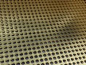 The picture shows a piece of round brass perforated mesh.