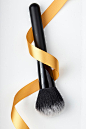 Close-Up Of Make-Up Brush And Ribbon Over White Background