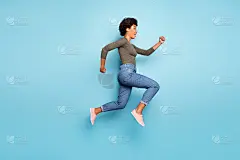 全身尺寸的照片，欢快迷人的可爱跳快快的女人跑到购物中心的销售穿着牛仔裤牛仔孤立在鲜艳的颜色蓝色背景