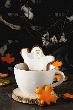 甜蜜的万圣节。热可可配上幽灵、树叶和南瓜形状的饼干。黑暗的背景。空间的文本。