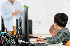 干细胞学校多民族男生与教师课时坐在计算机旁边的选择性焦点 