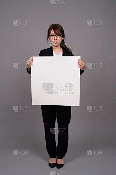 工作室拍摄的年轻美丽的亚洲女商人举着海报在灰色的背景