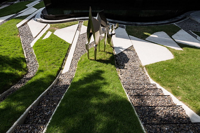 绿色土丘中的不锈钢小鹿雕塑