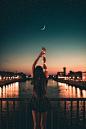 Woman in Black Dress Standing on Wooden Dock during Night Time