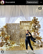 This may contain: a woman standing in front of a backdrop with gold balloons and streamers on it