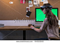 Young adult Caucasian female using holographic augmented reality glasses, creating a model on a computer screen. Green screen chroma key