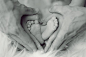 Grayscale Photo of Baby Feet With Father and Mother Hands in Heart Signs