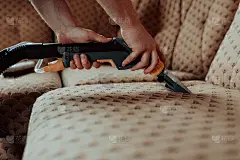 贴身管家手持现代吸尘器，用专业清洁剂清洗脏沙发。专业的家居春季大扫除概念