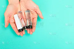 女修指甲。美丽的年轻女人的手与化妆品瓶在柔和的背景-图像