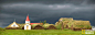 冰岛的葛劳姆农场，乌云笼罩着一栋草皮屋和一座教堂。