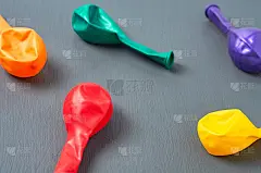 派对结束后，五颜六色的充气气球散落在灰色的水泥桌上或地板上。特写镜头