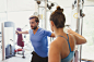 Female personal trainer guiding man doing cable chest fly at gym