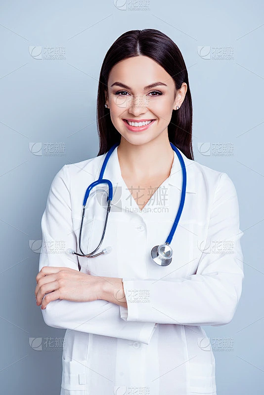 垂直肖像迷人的微笑年轻女医生制服在灰色的背景与交叉的手站素材-花瓣网