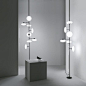 Floor – ceiling lamp with structure in glossy black nickel metal or bronze and shades in white blown glass.