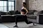 Pretty fit woman doing frontal lunges or squat exercise indoors in a flat
