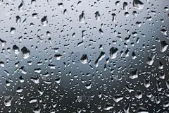 雨滴在玻璃上的纹理特写。微距透明水滴在蓝色背景。